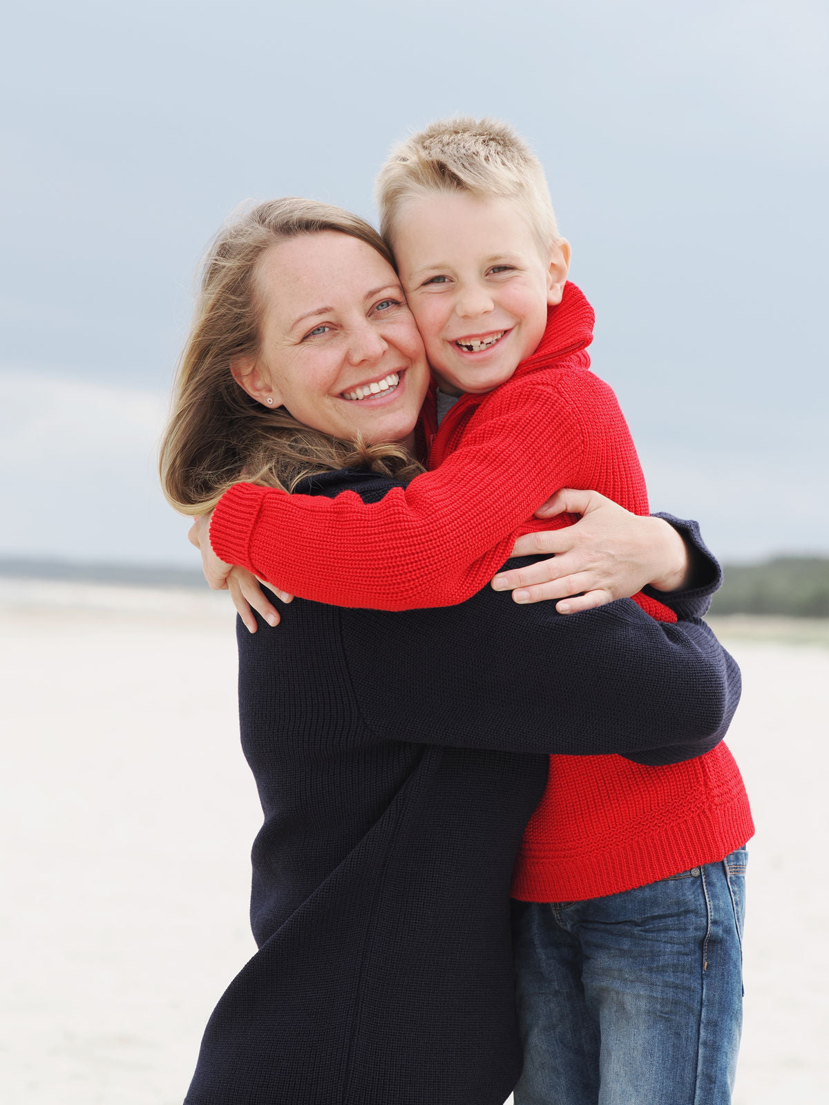 Mutter und Sohn halten sich innig in Troyern am Strand