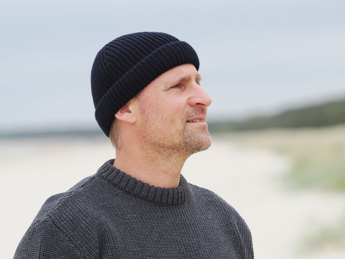 Mann mit Rollmütze am Strand