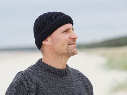 Mann mit Rollmütze am Strand