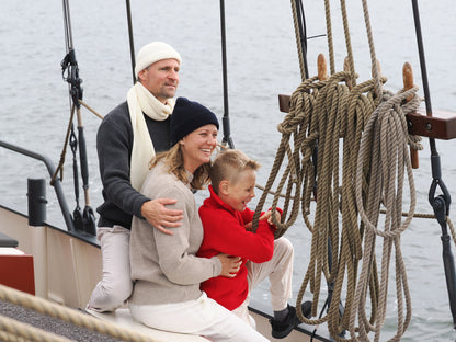 Familie mit Strickmützen, Schal und Troyern vom Blauen Peter an Bord eines Segelbootes