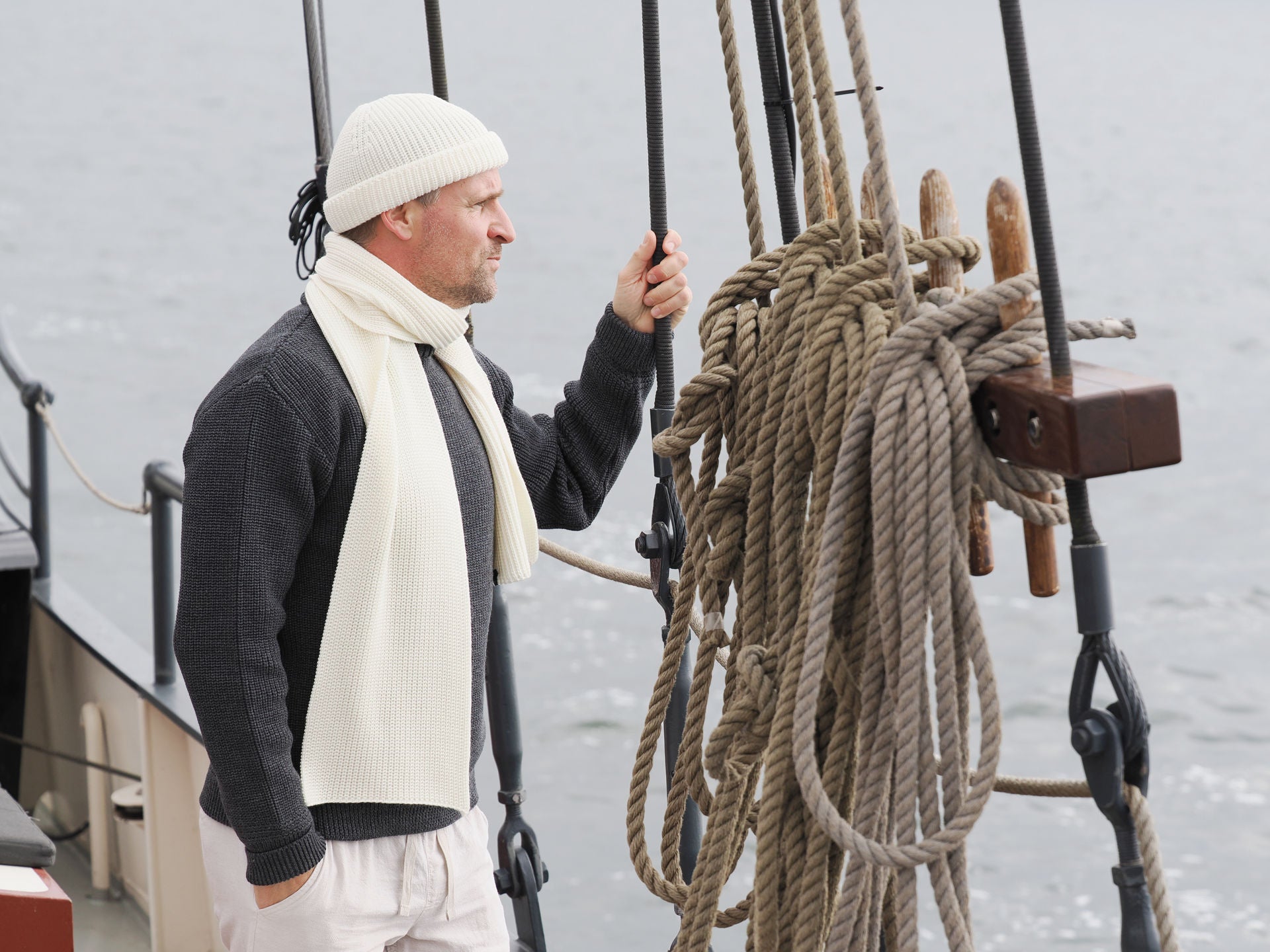 Mann mit Strickmütze und Schal von Blauer Peter auf einem Segelboot