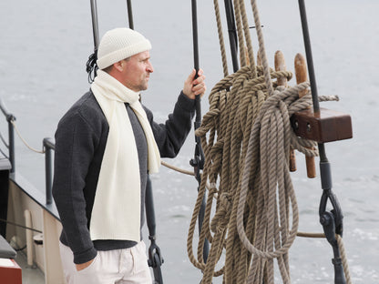 Mann mit Strickmütze und Schal von Blauer Peter auf einem Segelboot