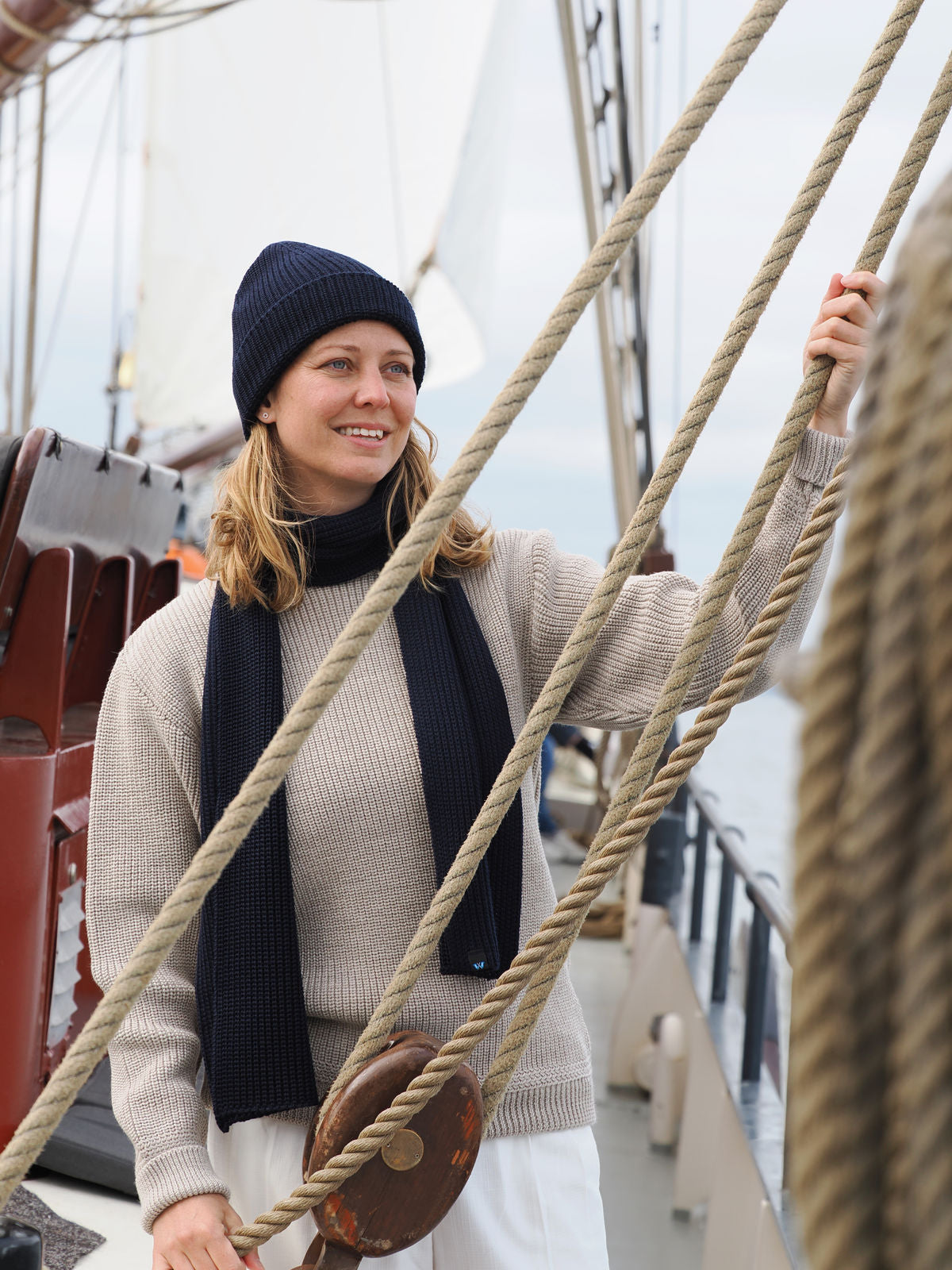 Frau entspannt mit Schal und Mütze an Deck