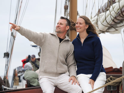 Paar trägt Kapuzen-Troyer-Jacke und Cashmere-Troyer und erkundet die Gegend mit dem Segelboot