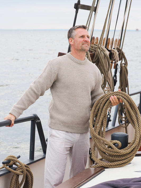 Mann mit Seilen und Rundhalstroyer an der Rehling eines Schiffes