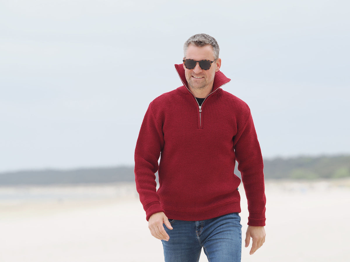 Mann mit hochgeklapptem Kragen im Metallzip-Troyer am Strand