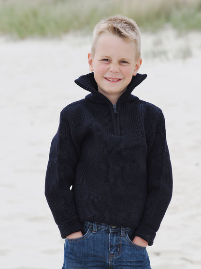 Junge mit dunklem Kinder-Troyer lässig am Strand