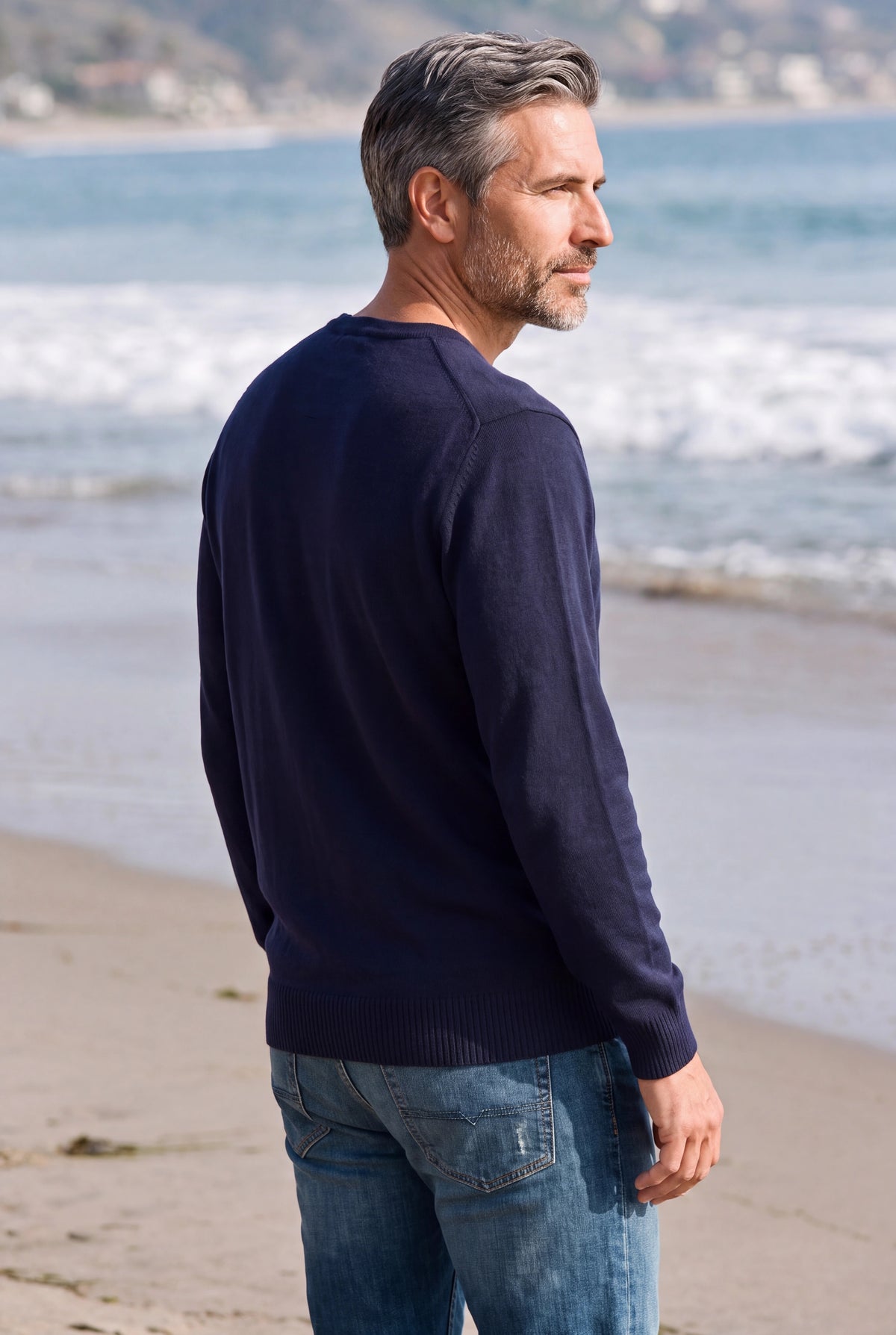 Mann mit Merino-V-Pullover blickt aufs Meer