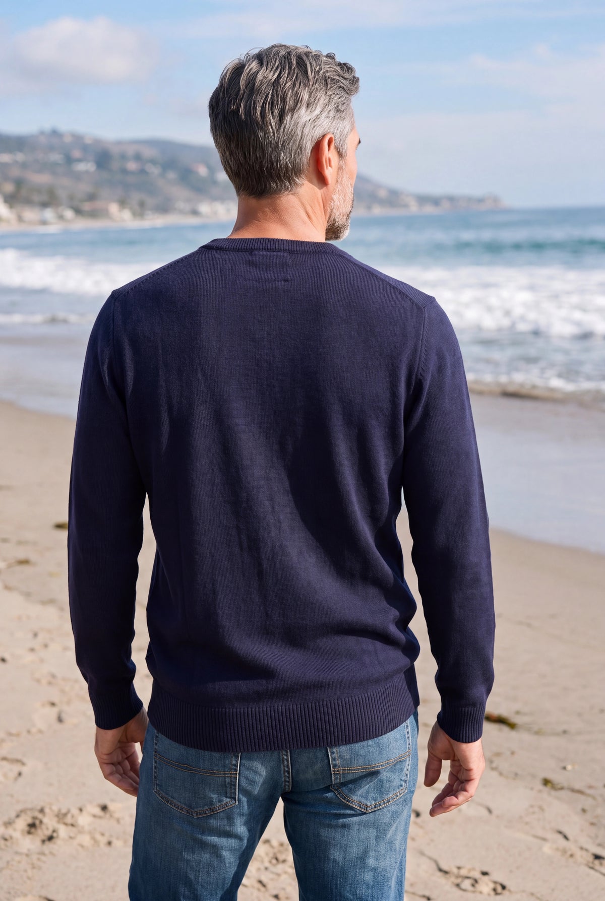 Mann mit Merino-V-Pullover von hinten am Meer