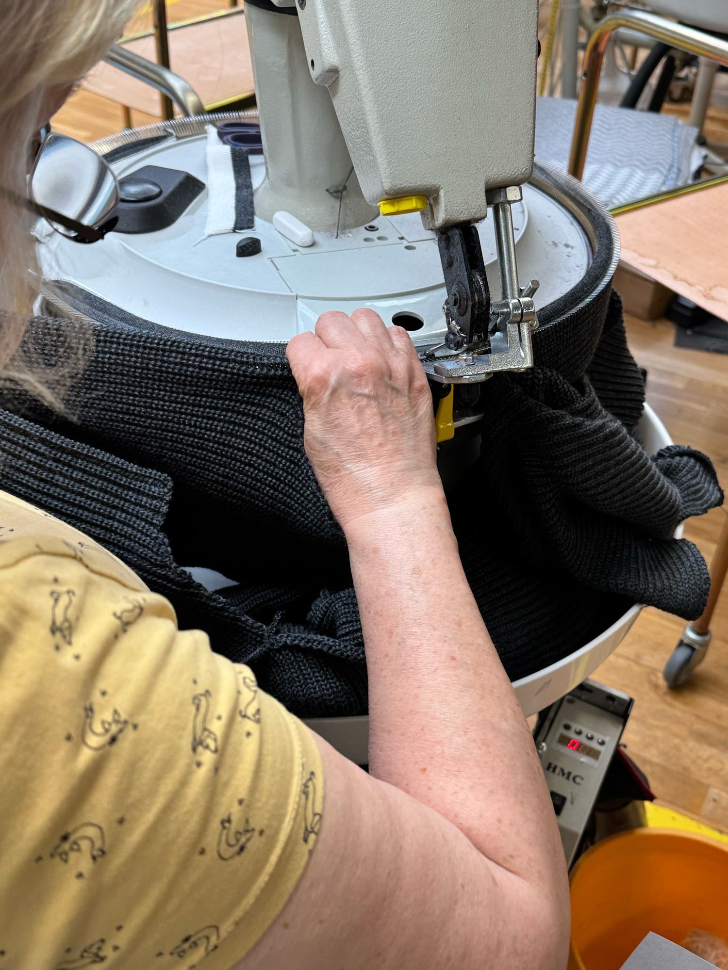 Manuelle Verarbeitung eines dunkelgrauen Strickpullovers an der Nähmaschine – hochwertige Troyer-Herstellung